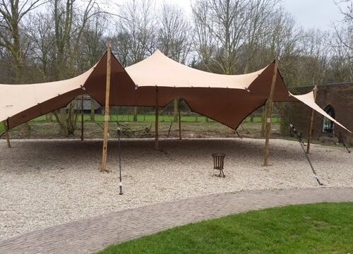 Luxe zandkleurige stretchtent of flextent op houten palen, beschikbaar in 6x9, 9x12 en 6x18 meter voor bruiloften en festivals.