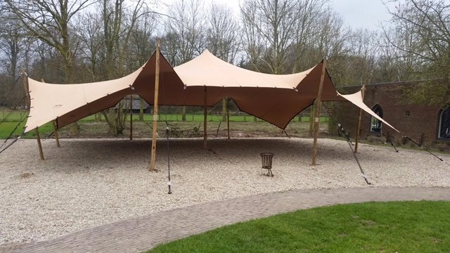 Luxe zandkleurige stretchtent of flextent op houten palen, beschikbaar in 6x9, 9x12 en 6x18 meter voor bruiloften en festivals.